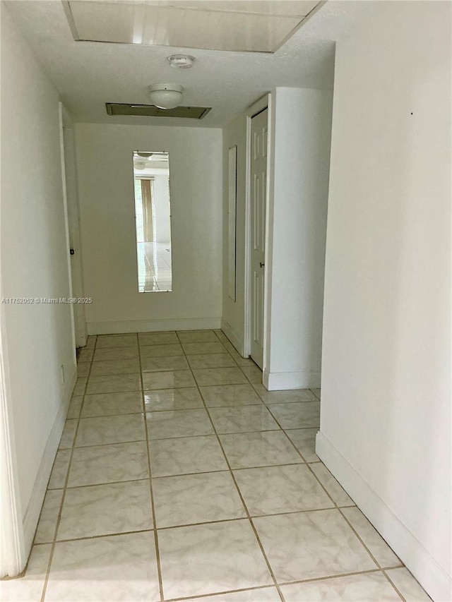 hallway with baseboards and light tile patterned floors