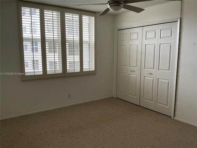 unfurnished bedroom with ceiling fan, carpet floors, a closet, and baseboards