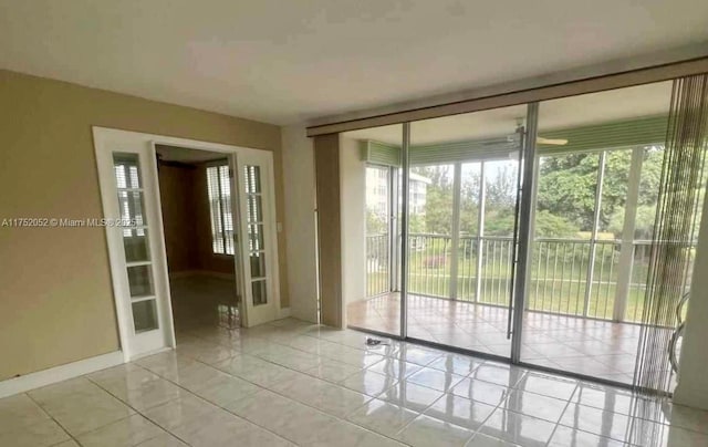 empty room featuring expansive windows, french doors, baseboards, and light tile patterned floors