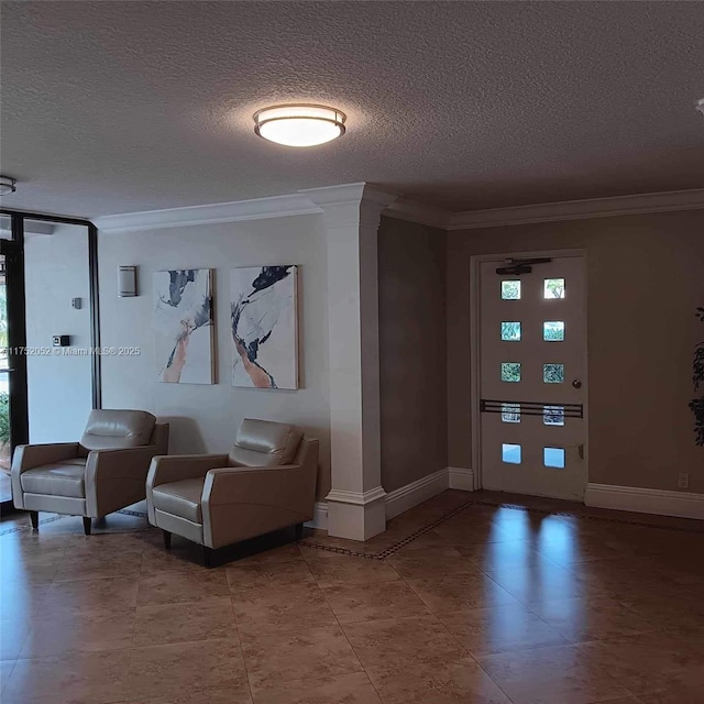 tiled entrance foyer featuring decorative columns, a textured ceiling, baseboards, and crown molding