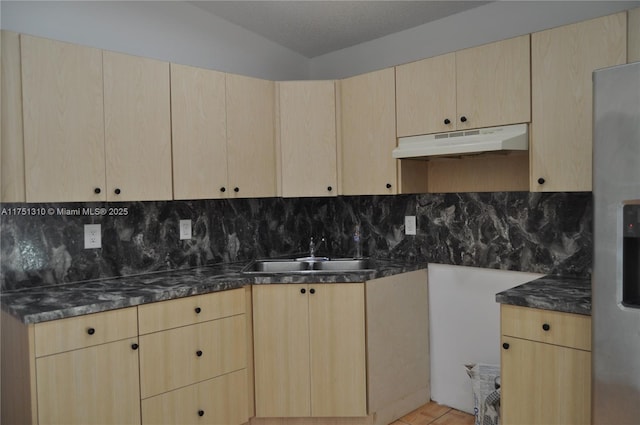 kitchen with backsplash, a sink, under cabinet range hood, and light brown cabinetry