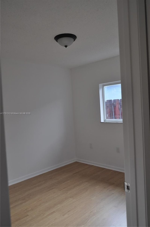 spare room with light wood-type flooring and baseboards