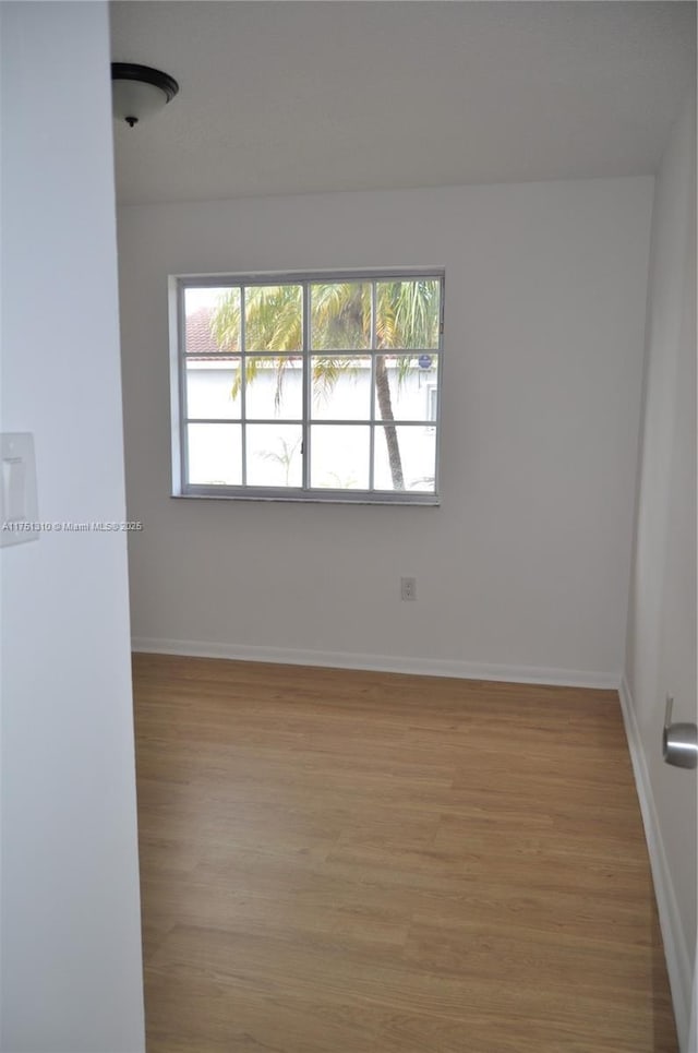 empty room with baseboards and light wood-style floors