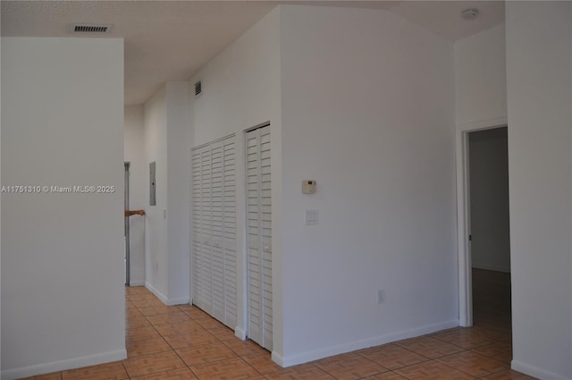 hallway with baseboards, electric panel, visible vents, and light tile patterned flooring