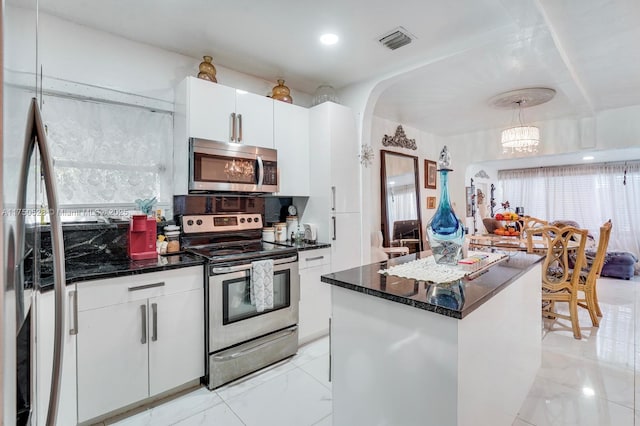 kitchen with visible vents, white cabinets, appliances with stainless steel finishes, a center island, and decorative light fixtures