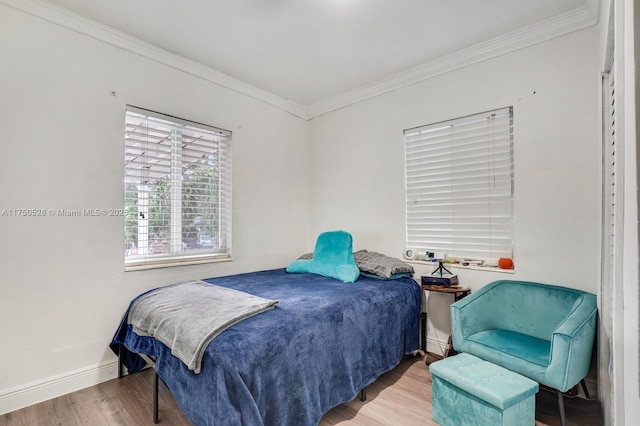 bedroom with crown molding, baseboards, and wood finished floors