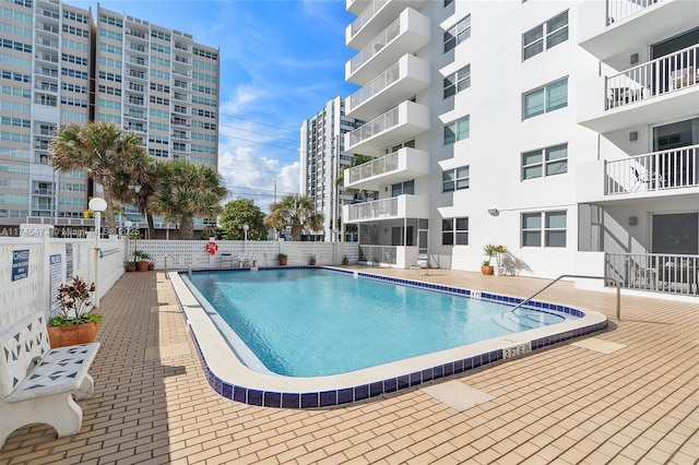 pool with a patio area and fence