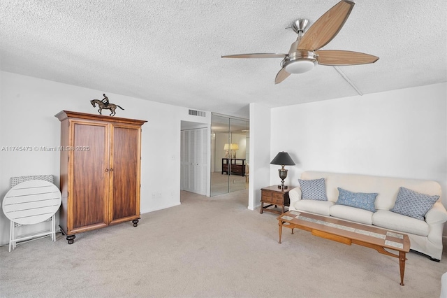 living room featuring a textured ceiling, visible vents, a ceiling fan, and light colored carpet