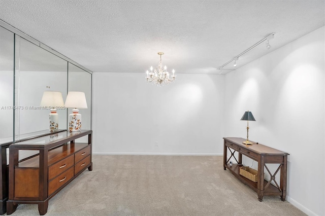 interior space with rail lighting, light colored carpet, a notable chandelier, and a textured ceiling