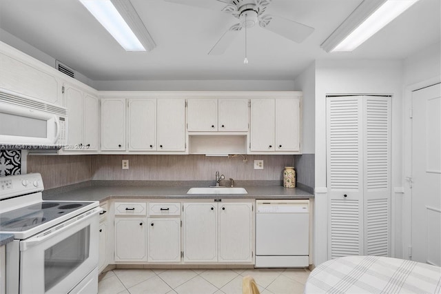 kitchen featuring dark countertops, light tile patterned flooring, a sink, ceiling fan, and white appliances