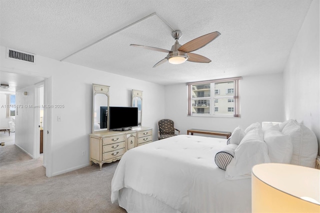 bedroom with a textured ceiling, light carpet, visible vents, baseboards, and a ceiling fan