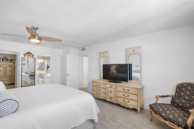 bedroom with visible vents, connected bathroom, light colored carpet, ceiling fan, and a textured ceiling