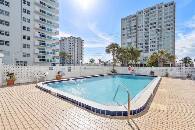 community pool with a patio area and fence