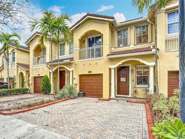 view of front of house with decorative driveway, a tiled roof, an attached garage, and stucco siding