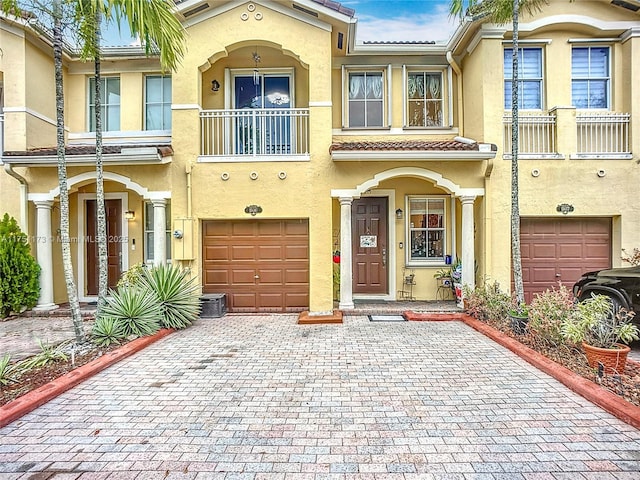 view of front of property with an attached garage, a tiled roof, decorative driveway, and stucco siding