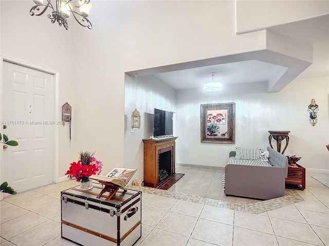 living room with an inviting chandelier, a fireplace, baseboards, and light tile patterned floors