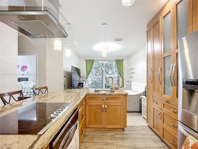 kitchen with light stone counters, hanging light fixtures, appliances with stainless steel finishes, brown cabinetry, and a sink