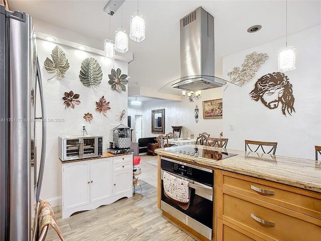 kitchen featuring hanging light fixtures, appliances with stainless steel finishes, island exhaust hood, and light stone countertops