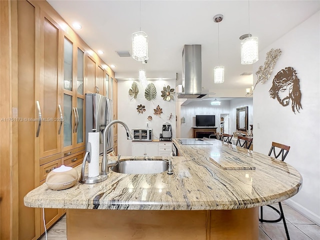 kitchen with island range hood, light stone counters, a breakfast bar, hanging light fixtures, and a sink