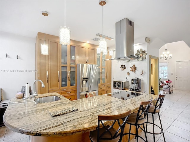 kitchen with black electric cooktop, island range hood, a sink, hanging light fixtures, and stainless steel fridge