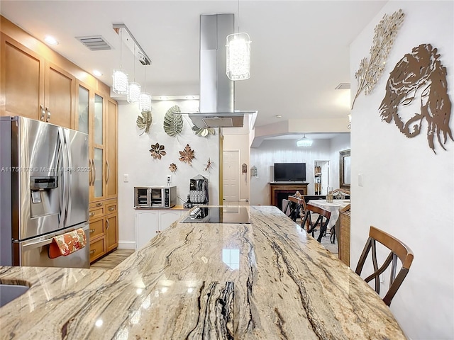 kitchen with light stone counters, a breakfast bar area, stainless steel fridge with ice dispenser, glass insert cabinets, and pendant lighting