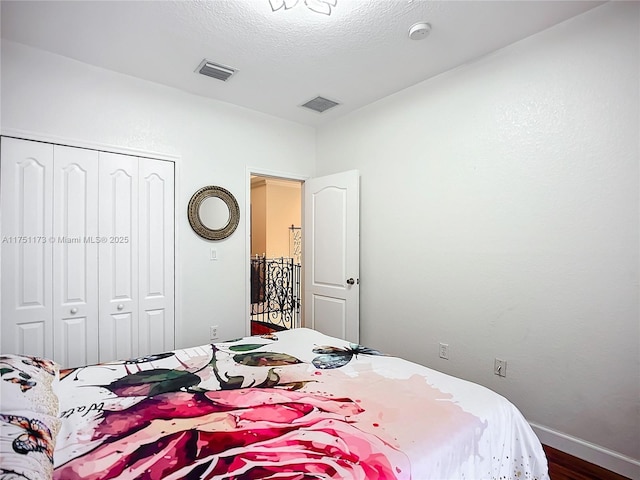 bedroom featuring a textured ceiling, a closet, visible vents, and baseboards