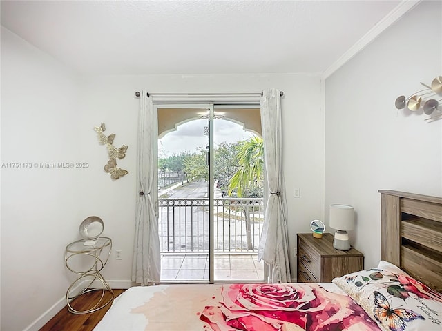 bedroom featuring access to exterior, baseboards, and wood finished floors