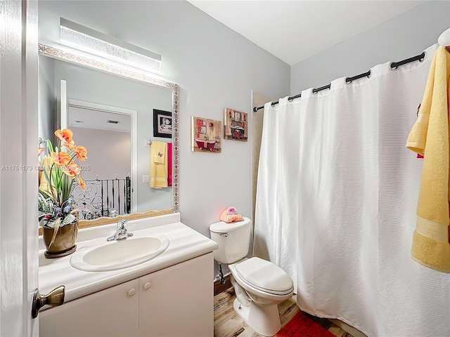 bathroom with toilet, wood finished floors, and vanity