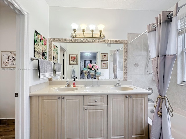 full bathroom with double vanity, tiled shower / bath combo, and a sink