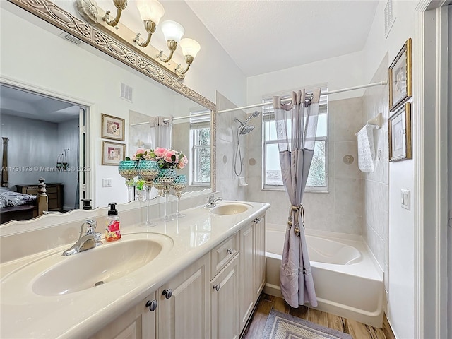 bathroom with shower / bath combo, visible vents, and a sink