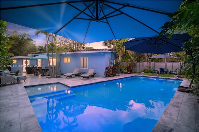 pool at dusk featuring a patio area, a fenced backyard, and a fenced in pool