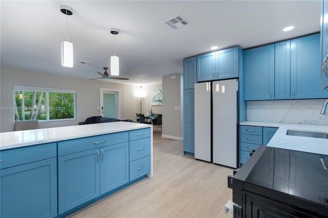 kitchen with a sink, visible vents, light countertops, freestanding refrigerator, and pendant lighting