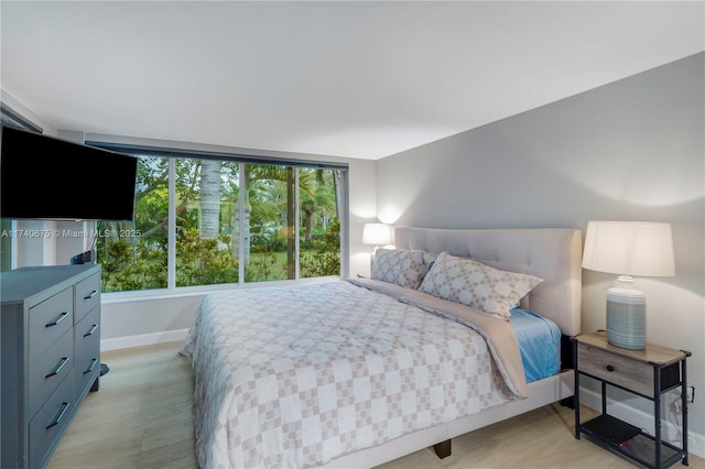 bedroom with baseboards and light wood finished floors