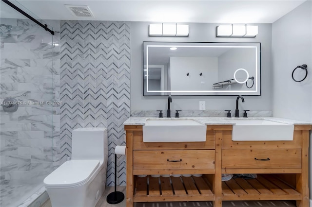 bathroom with toilet, double vanity, a sink, and visible vents