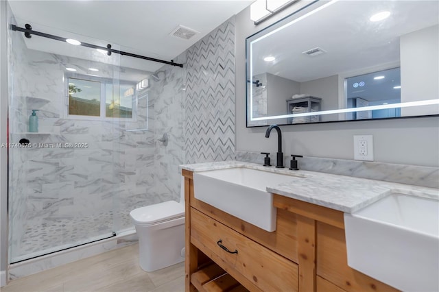 bathroom featuring visible vents, a sink, a shower stall, and double vanity