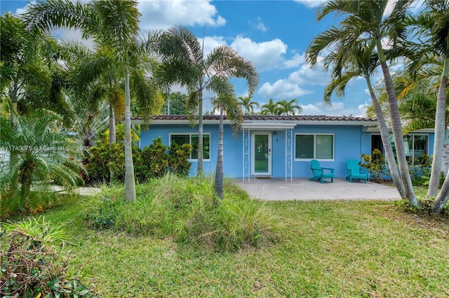 back of property featuring a patio area, a yard, a tiled roof, and stucco siding