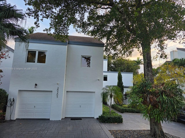 view of side of property featuring an attached garage, decorative driveway, and stucco siding