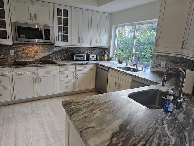 kitchen featuring stainless steel appliances, glass insert cabinets, a sink, and a peninsula