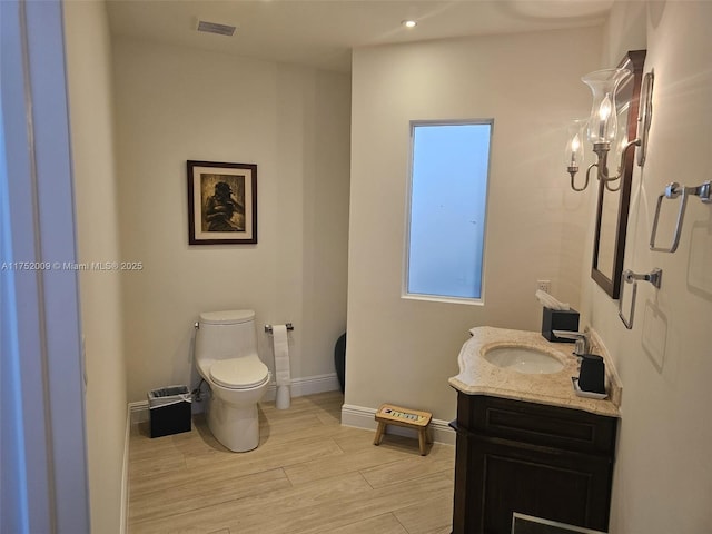 bathroom with visible vents, baseboards, toilet, wood finished floors, and vanity