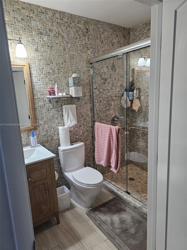 full bath featuring toilet, a stall shower, tile walls, and vanity