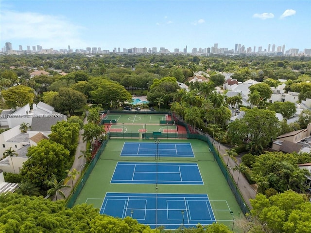 view of tennis court featuring a view of city and fence