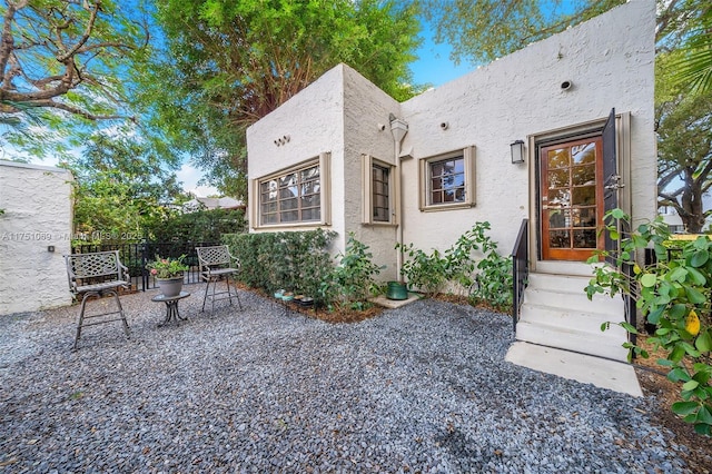 view of front facade with entry steps, fence, a patio, and stucco siding