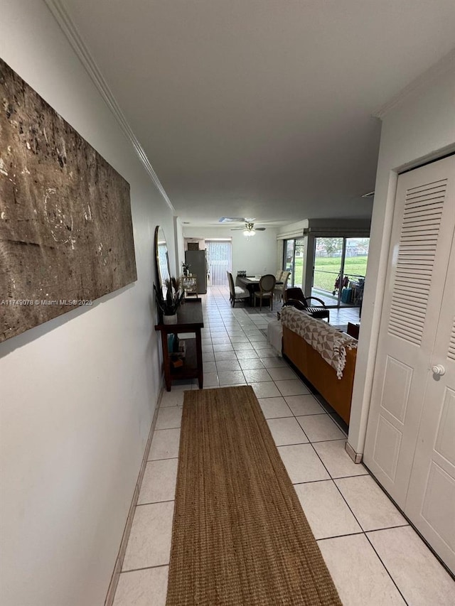 corridor featuring light tile patterned floors, baseboards, and ornamental molding