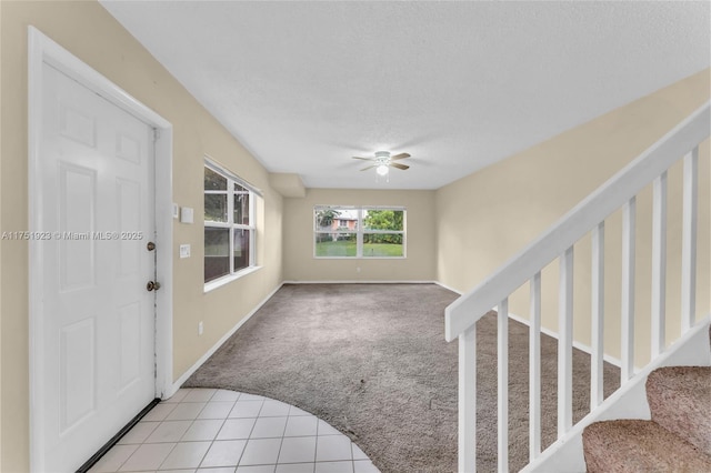 foyer with ceiling fan, stairway, a textured ceiling, and light colored carpet