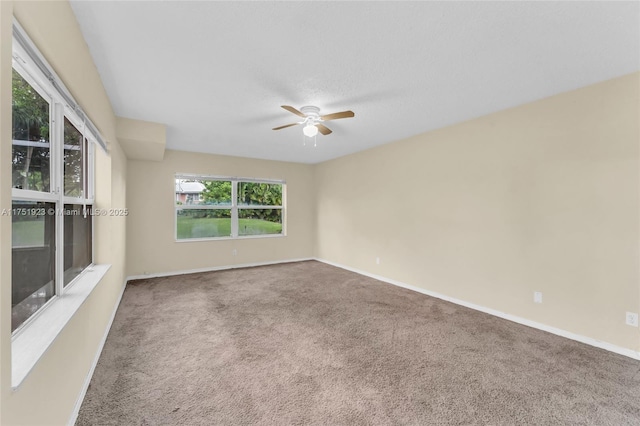 carpeted empty room featuring ceiling fan and baseboards