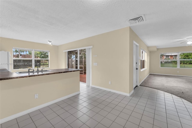 empty room with plenty of natural light, visible vents, a sink, and light tile patterned flooring