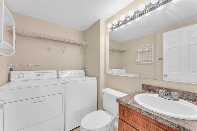 bathroom with washer and clothes dryer, vanity, and toilet