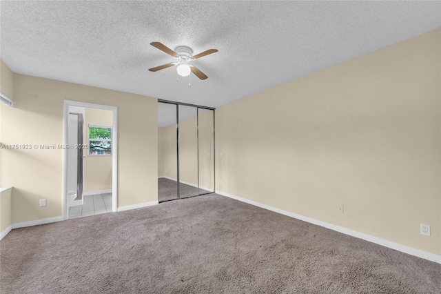 unfurnished bedroom with a closet, light carpet, connected bathroom, a textured ceiling, and baseboards