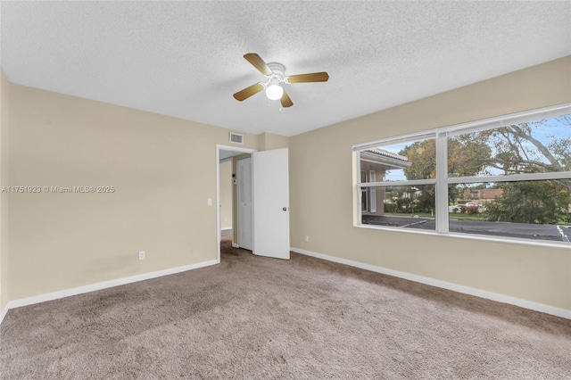 carpeted empty room with a ceiling fan, baseboards, visible vents, and a textured ceiling