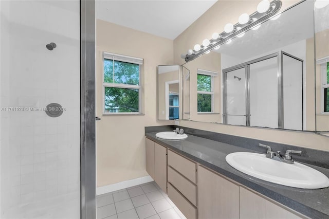 full bath with a wealth of natural light, a sink, a shower stall, and tile patterned floors